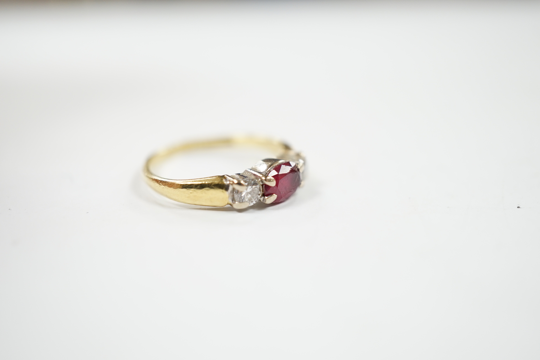 A modern 18ct gold, ruby and diamond set three stone ring, shank misshapen, gross weight 2.9 grams.